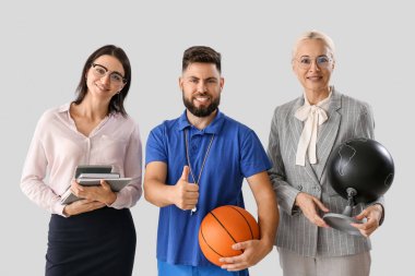 Teachers with ball, books and globe on light background