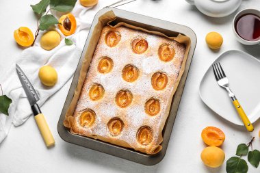 Baking tray with tasty apricot pie and fresh fruits on light background