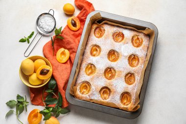 Composition with tasty apricot pie, fresh fruits, mint and sugar powder on light background