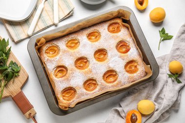 Baking tray with tasty apricot pie on light table