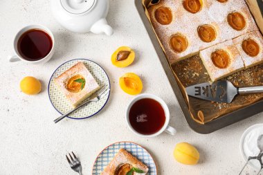Composition with tasty apricot pie and cups of tea on light background