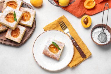 Plate with tasty apricot pie on light background