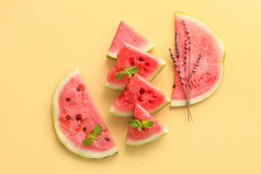 Slices of watermelon with mint and flowers on color background