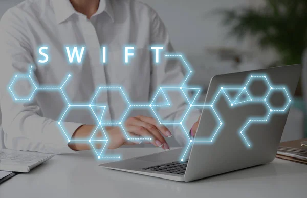 Young woman with laptop in office and virtual screen with word SWIFT