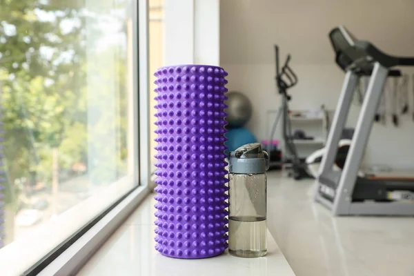 Foam roller with bottle of water on windowsill in gym