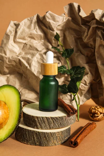 Composition with bottle of essential oil, cinnamon sticks and crumpled paper sheet on color background