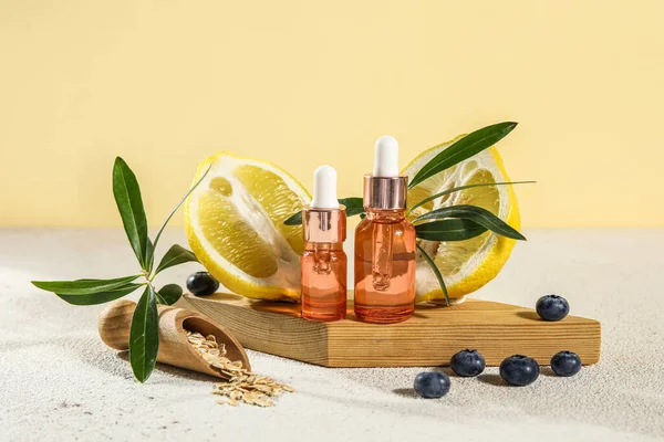 Composition with bottles of essential oil, blueberry, oatmeal and lemon on table