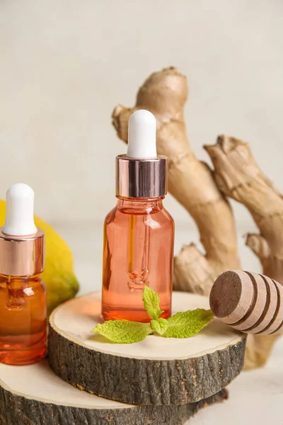 Bottles of essential oil on wooden stands against light background, closeup