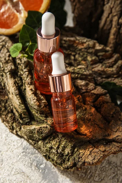 Bottles of essential oil and tree bark on table, closeup