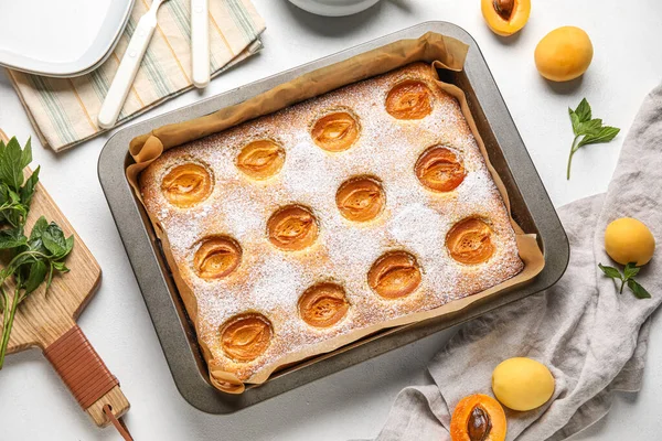 Baking tray with tasty apricot pie on light table