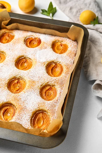 Baking tray with tasty apricot pie on light table, closeup