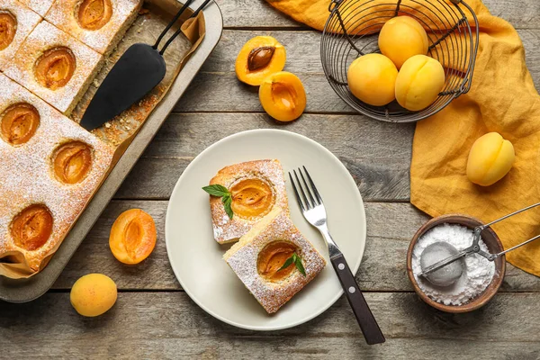 Composition with tasty apricot pie, fresh fruits and sugar powder on wooden background
