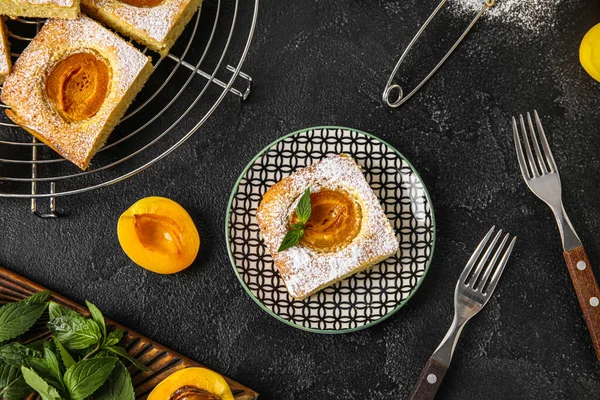 Plate with piece of tasty apricot pie on dark background