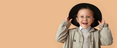 Portrait of stylish little girl in autumn clothes on beige background with space for text