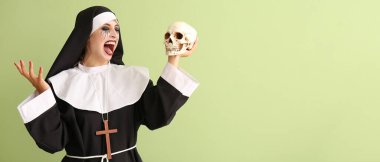 Woman dressed for Halloween as nun with skull on green background with space for text