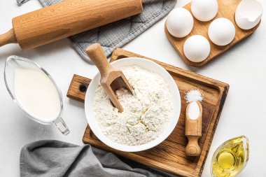 Bowl of flour, sugar and milk on light background