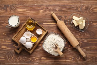 Composition with ingredients for baking and rolling pin on wooden background