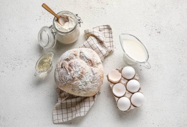 Fresh bread and ingredients for baking on light background