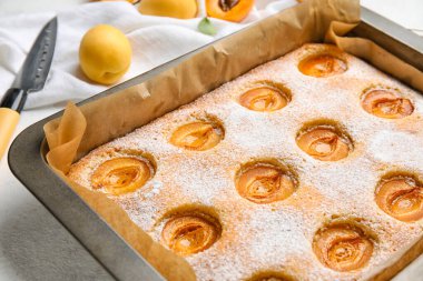 Baking tray with tasty apricot pie on table, closeup