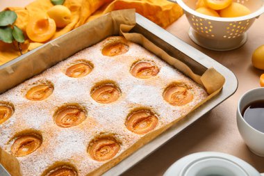 Baking tray with tasty apricot pie on color table, closeup