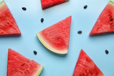 Slices of tasty watermelon with seeds on blue background