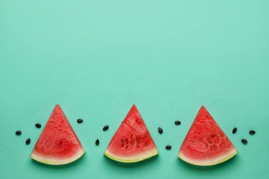 Slices of tasty watermelon with seeds on green background