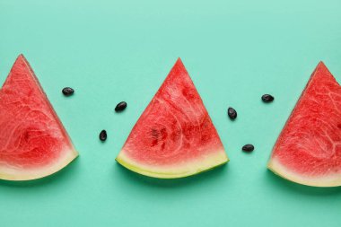 Slices of tasty watermelon with seeds on green background