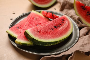 Plate with slices of watermelon and napkin on beige background, closeup