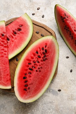 Cutting board with slices of watermelon on grunge background