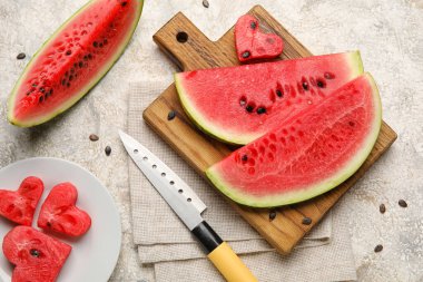 Plate, cutting board with slices of watermelon, knife and napkin on grunge background