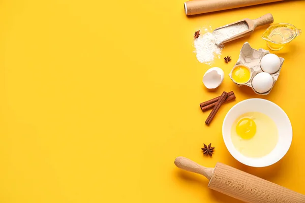 Different ingredients for baking and rolling pin on color background