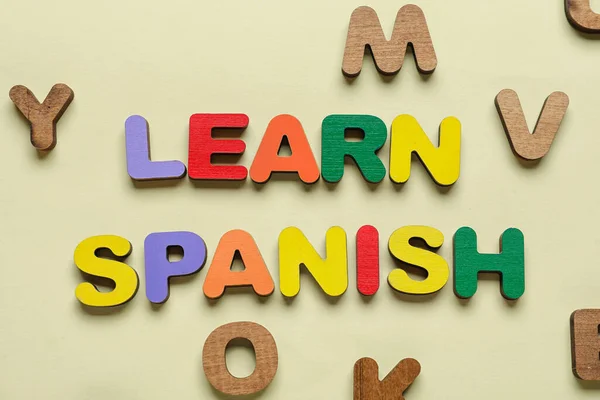 Text LEARN SPANISH with letters on beige background