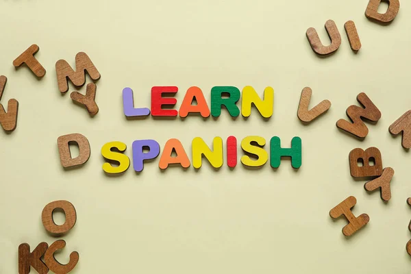 Text LEARN SPANISH with letters on beige background