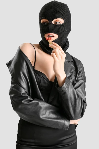 Young Woman Balaclava Applying Red Lipstick Light Background — Stockfoto