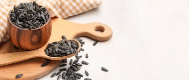 Bowl and spoon with sunflower seeds on white background with space for text