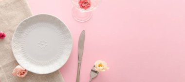Simple table setting with flowers on pink background with space for text