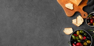 Bowls of delicious olives and bread on grey background with space for text