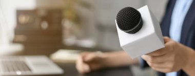 Ofisinde mikrofonu olan kadın gazeteci, yakın plan.