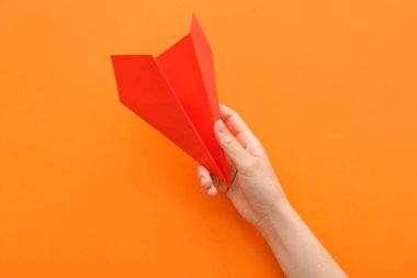Woman with red paper plane on orange background