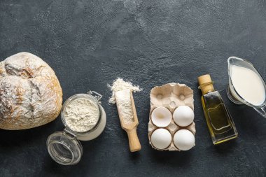 Fresh bread with raw dough and ingredients on dark background