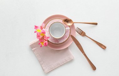 Table setting with cup and alstroemeria flowers on white background