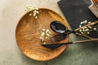 Table setting with wooden plate and gypsophila flowers on white and green background, closeup