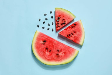 Slices of tasty watermelon with seeds on blue background