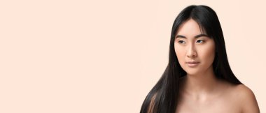 Young Asian woman with beautiful long hair on light beige background with space for text