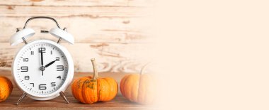 Alarm clock and pumpkins on wooden background. Banner for design