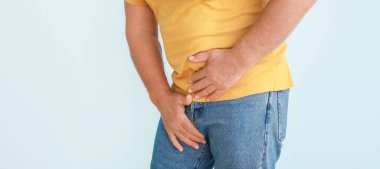 Man with urologic disease on light blue background, closeup