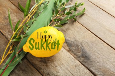 Greeting card with Sukkot festival symbols on wooden background