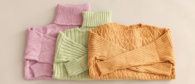 Folded warm sweaters on light background