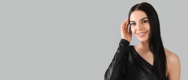 Young woman with beautiful dark hair on grey background with space for text
