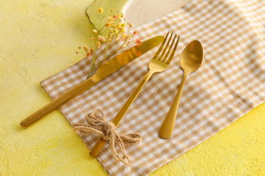 Table setting with flower decor on yellow background